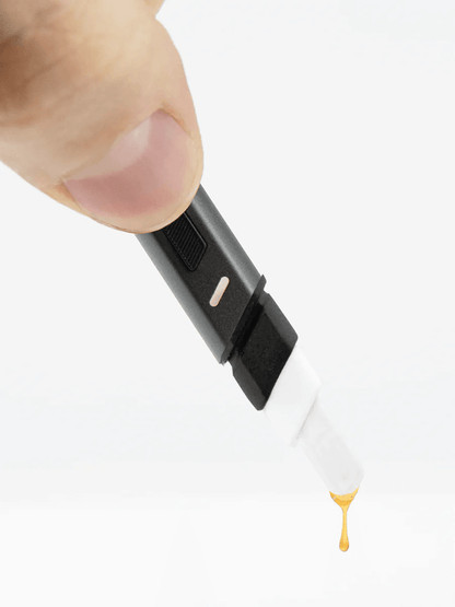 User holding Puffco Hot Knife heated loading tool, showcasing a drop of extract at the tip.