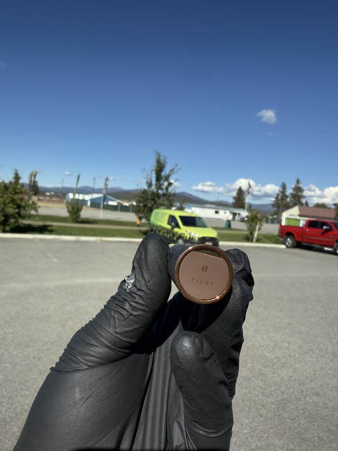 Puffco X Palmers Powders Pivot - LV Power Coated held in gloved hand against a clear blue sky.
