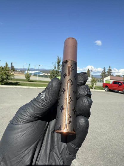 Puffco X Palmers Powders Pivot - LV Power Coated held in a gloved hand outdoors with a scenic background.