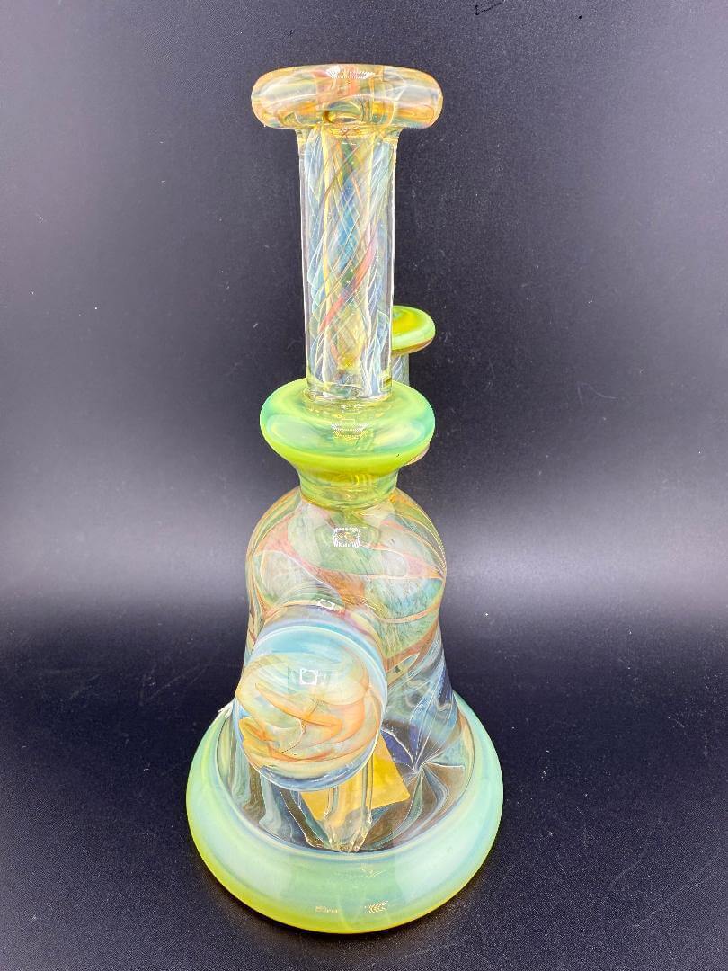 Handmade Pugsley Glass rig with vibrant green accents and intricate swirls, 10mm 90° joint, created in Spokane, WA.
