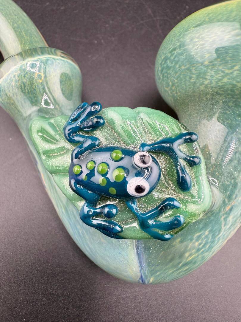 Rosie Works Sherlock Pipe - Green Frit w/ Leaf & Blue Frog Attachment showcasing a blue frog on a leaf.