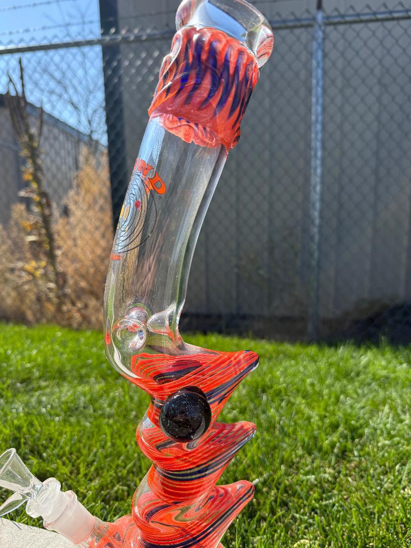 Round Glass Orange And Blue Spiked Bubble beaker 14mm 45° with vibrant colors and unique texture displayed outdoors.