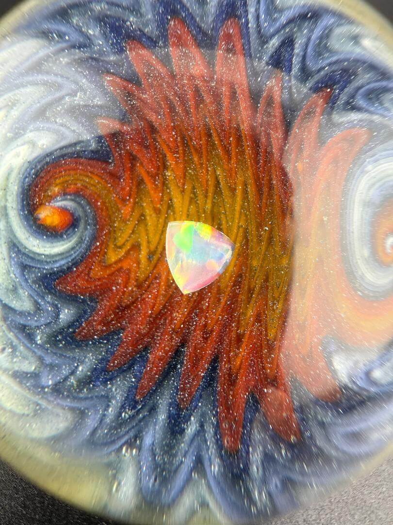 Close-up of a Royals Glass OG Dichoric Wig Wag XL 50mm Marble featuring an opal center against a vibrant swirl background.