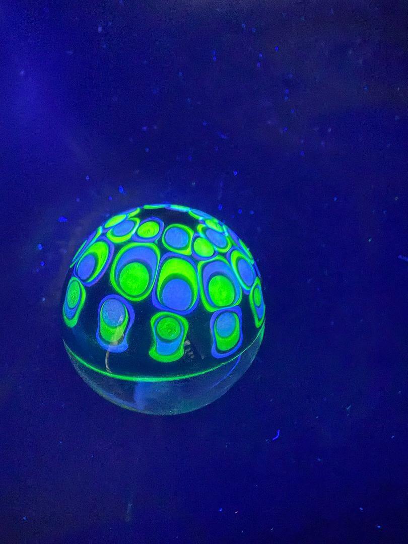 Siliceous Boro Jockey (SBJ) Marble - 42mm UV Retti Cello w/ UV Dot Stack Backer glowing under UV light.