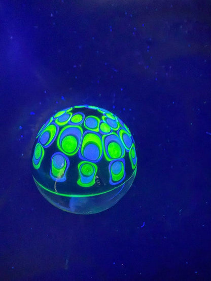 Siliceous Boro Jockey (SBJ) Marble - 42mm UV Retti Cello w/ UV Dot Stack Backer glowing under UV light.