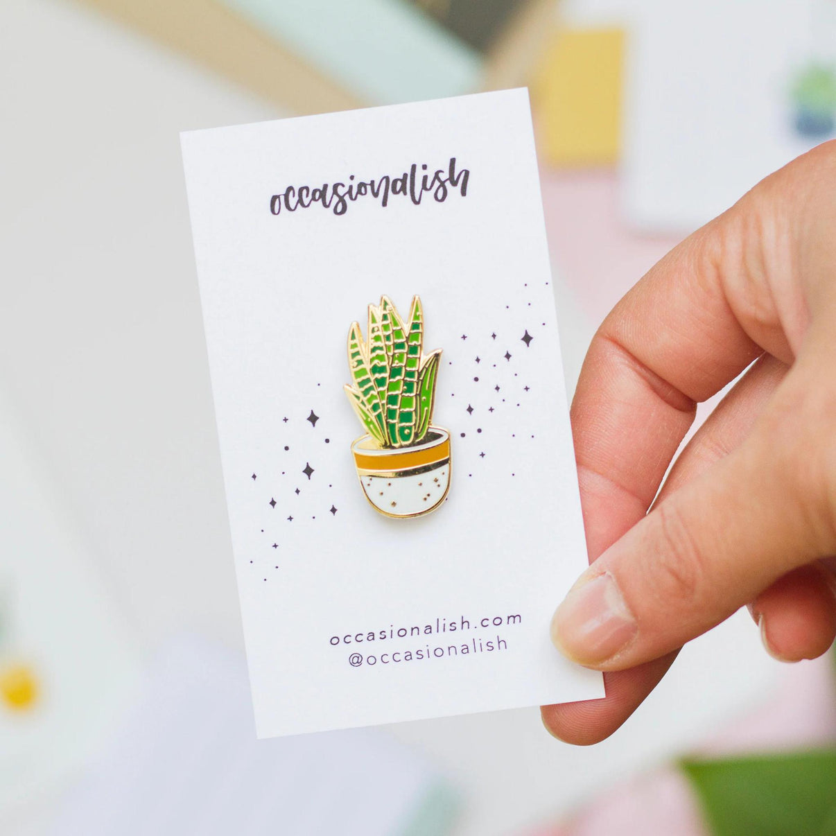 Occasionalish Enamel Pin - Snake Plant held in hand, showcasing a colorful snake plant design in a pot.