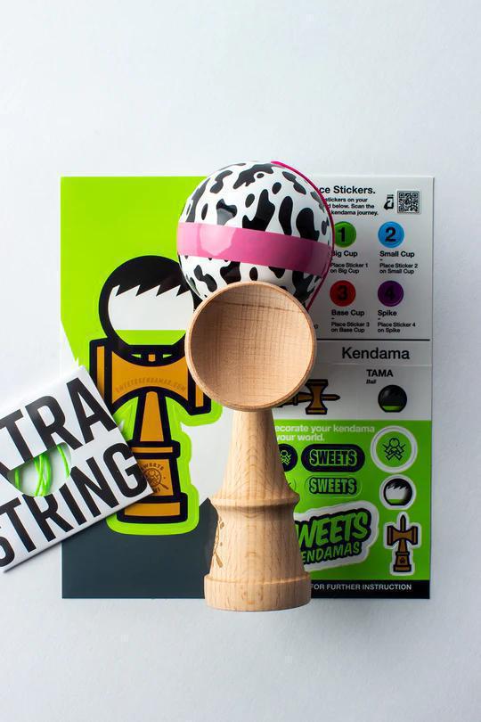 Sweets Kendama - Cow Print with Stickers and Extra String on a colorful instruction background.