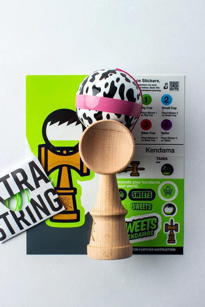 Sweets Kendama - Cow Print with Stickers and Extra String on a colorful instruction background.