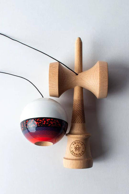 Sweets Kendama Illusion Amped featuring red and white ball on a wooden handle with intricate design details.