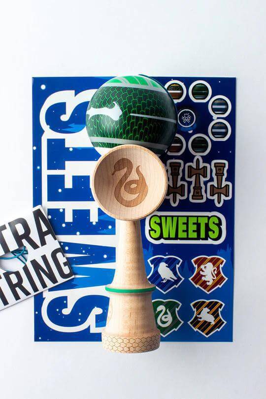 Sweets Kendama Sweets Lab V35 Sticky Clear with serpent design and stickers on a blue background.
