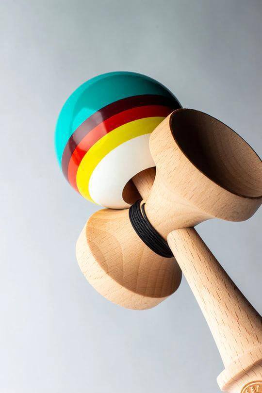 Sweets Kendama Triple Stripe Legend Sticky Clear with vibrant colored tama and beech wood handle displayed at an angle.