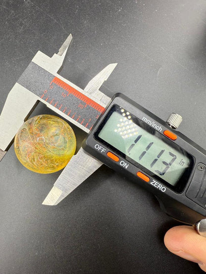 Taco Glass Marble - Fumed Dichro 1.1" being measured with calipers showing 1.13 inches in diameter.