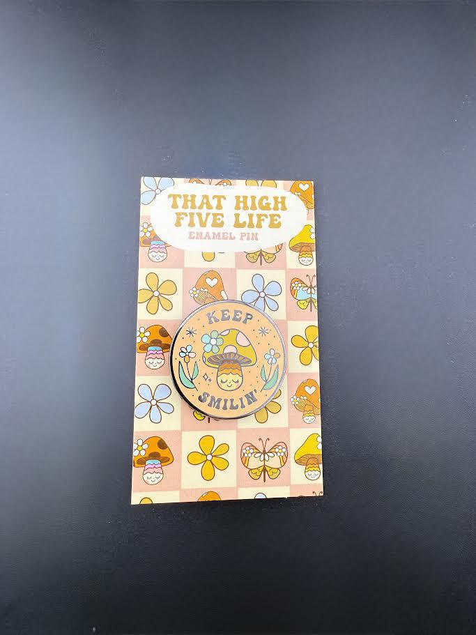 That High Five Life Enamel Pin - Keep Smilin' Hard on a colorful card with flowers and butterflies.