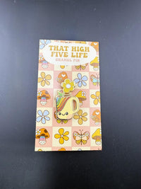 That High Five Life Enamel Pin - Rainbow Mug on a colorful display card with flowers and mushrooms.