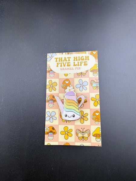 That High Five Life Enamel Pin - Teapot displayed on a colorful backing with flowers and hearts.