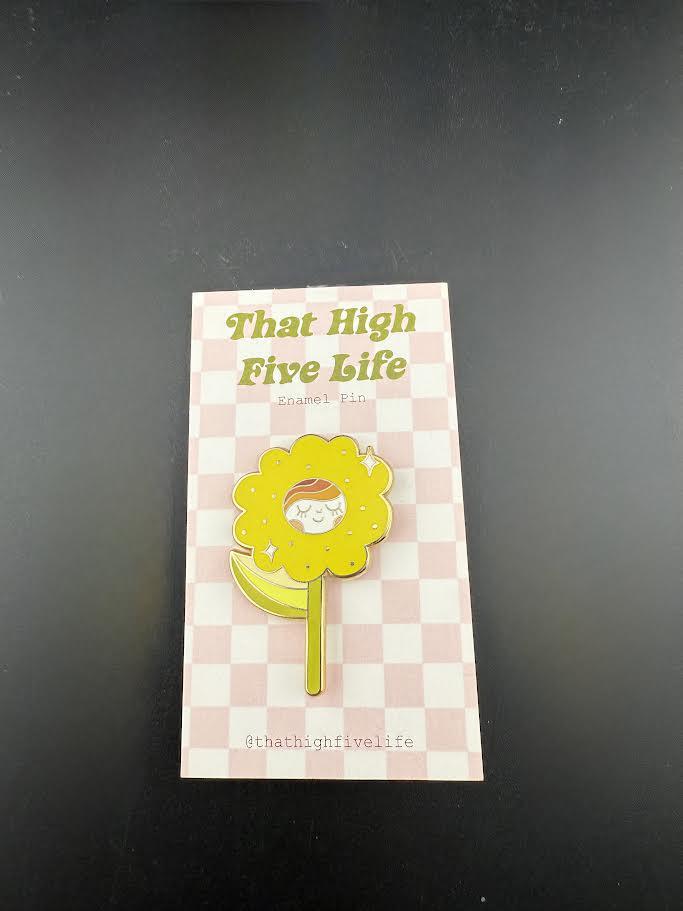 That High Five Life Enamel Pin - Yellow Happy Flower displayed on a checkered card, showcasing its vibrant and cheerful design.