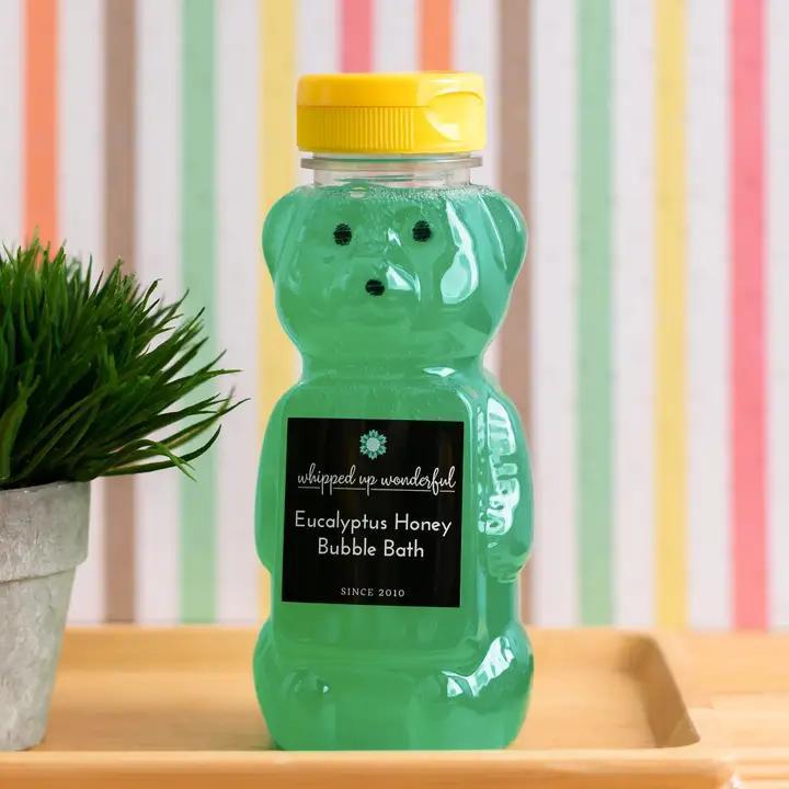 Whipped Up Wonderful Eucalyptus Honey Bubble Bath in a bear-shaped bottle surrounded by greenery.