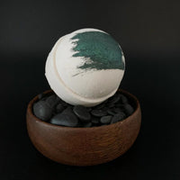 Whipped Up Wonderful - Pipe Smoke Recharge Bomb bath bomb in a wooden bowl with black pebbles.