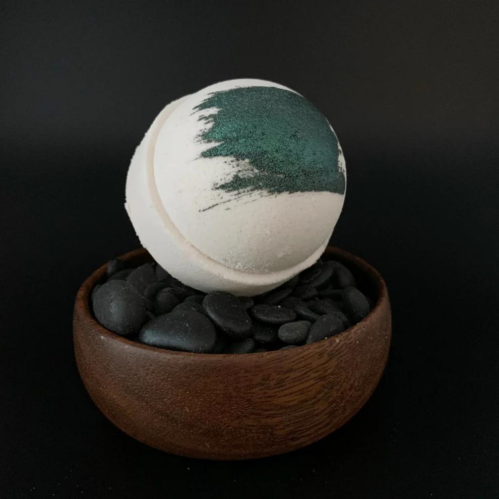 Whipped Up Wonderful - Pipe Smoke Recharge Bomb bath bomb in a wooden bowl with black pebbles.