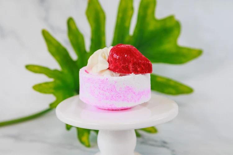 Whipped up Wonderful Strawberries And Cream Waffle Bath Bomb on a display stand with a leaf backdrop.
