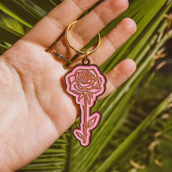 Wild Rose Keychain - Rose held in a hand with a vibrant pink enamel design and polished gold finish.