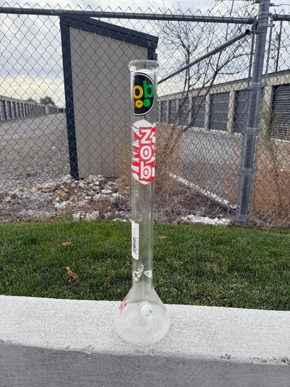 Zob Glass 24" OG Beaker Flower Piece standing on the ground against a backdrop of storage units.