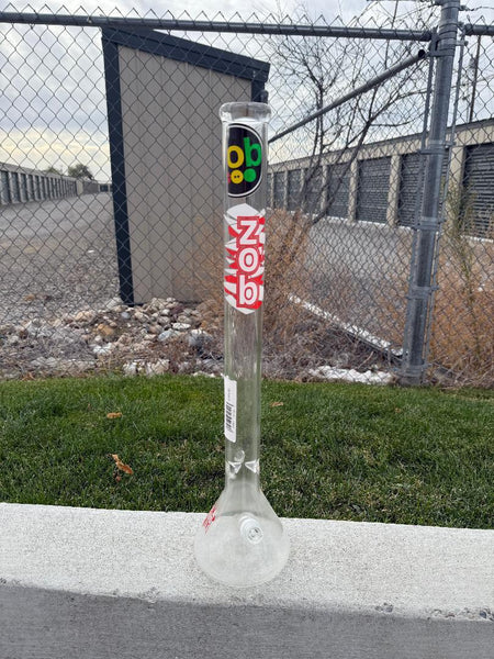 Zob Glass 24" OG Beaker Flower Piece standing on the ground against a backdrop of storage units.