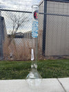 Zob Glass 24" OG Beaker Flower Piece displayed outdoors against a chain-link fence backdrop.