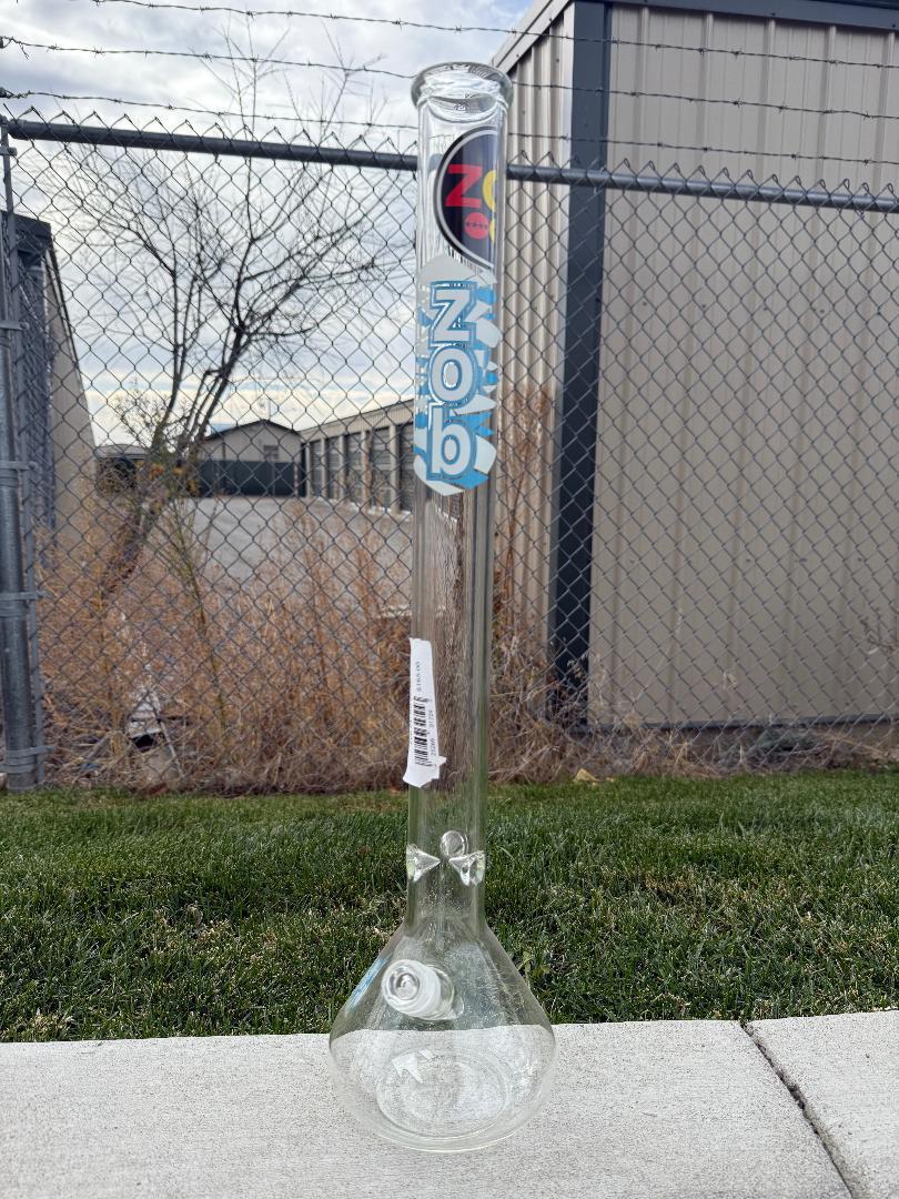 Zob Glass 24" OG Beaker Flower Piece displayed outdoors against a chain-link fence backdrop.